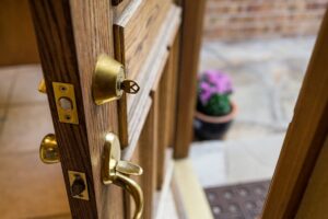 Key in a brass deadbolt on an open wooden front door