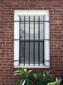 Black steel security bars on a window of a brick rowhouse