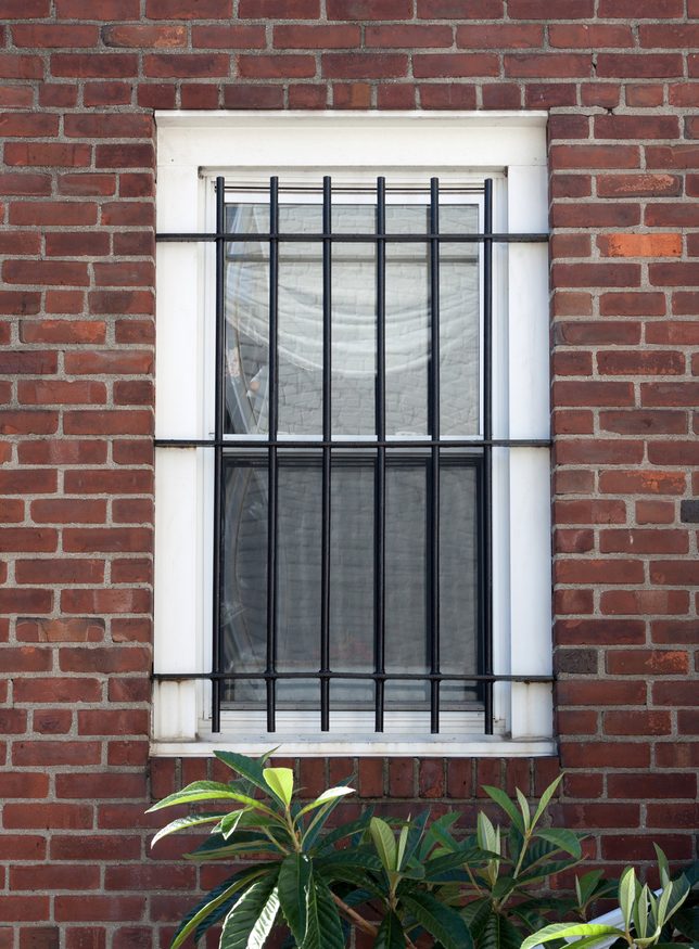 Black steel security bars on a window of a brick rowhouse